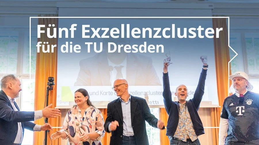 Picture of 5 cheering people in front of a video of a press conference projected on the wall